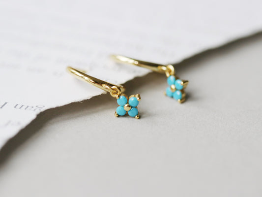 Shan&Co's Gold Vermeil Four Leaf Clover Turquoise CZ Dangle Huggies Earrings, featuring a delicate four-leaf clover charm adorned with turquoise crystal zirconia, perfect for adding a touch of elegance and luck to any outfit.